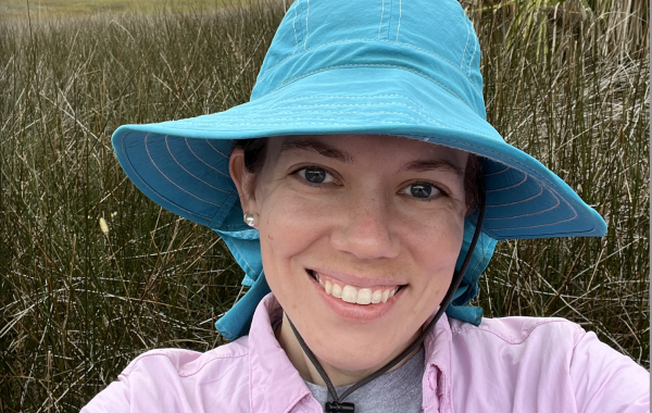 A woman in a blue bucket hat in front of a marsh