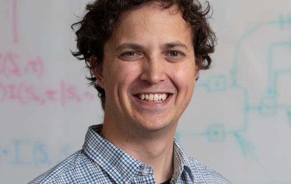 Simon Sponberg smiling in front of a whiteboard.