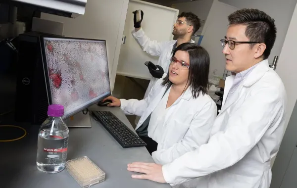 Three Georgia Tech researchers working together in the lab on cancer research