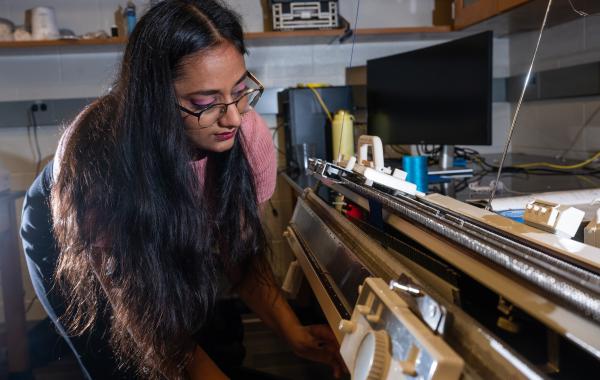 Former Matsumoto Group member Krishma Singal operates a knitting machine used to create fabric samples for a previous study. Singal recently graduated from Georgia Tech with her Ph.D. (Photo Credit: Allison Carter)